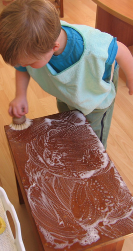 Seorang anak laki-laki menyikat meja